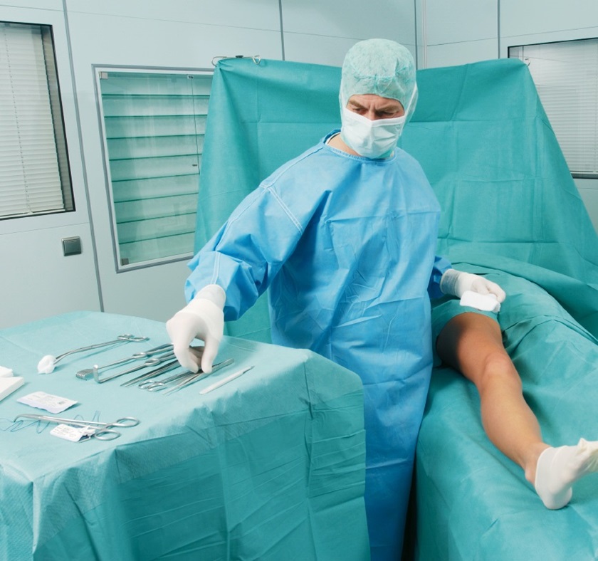 A doctor prepares the surgery of a leg wound.  