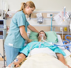 Pflegerin schüttelt Kissen eines Patienten in der Intensivstation auf