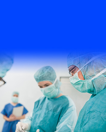 Záber na operatérov v priebehu zákroku. V ľavom hornom rohu vidieť logo divízie Prevencia infekcií na operačných sálach v podobe štítu.