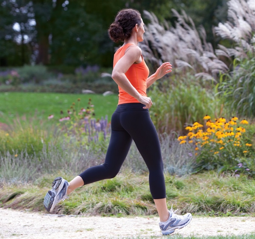 Une femme en tenue de sport fait du jogging dans un parc fleuri