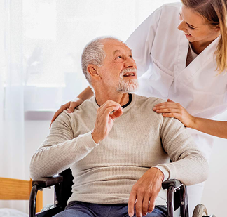 Pflegerin beugt sich über die Schulter eines im Seniors im Rollstuhl