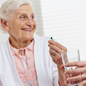 Seniorin erhält Tablette von Pflegerin