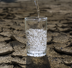 Wasserglas auf aufgerissenem Wüstenboden